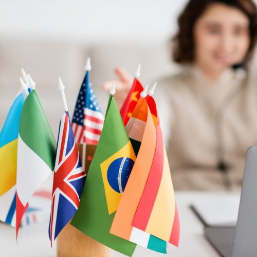Selective,Focus,Of,Various,International,Flags,Near,Blurred,Laptop,And